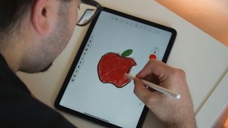 Someone using the iPad Air 5 to draw an apple