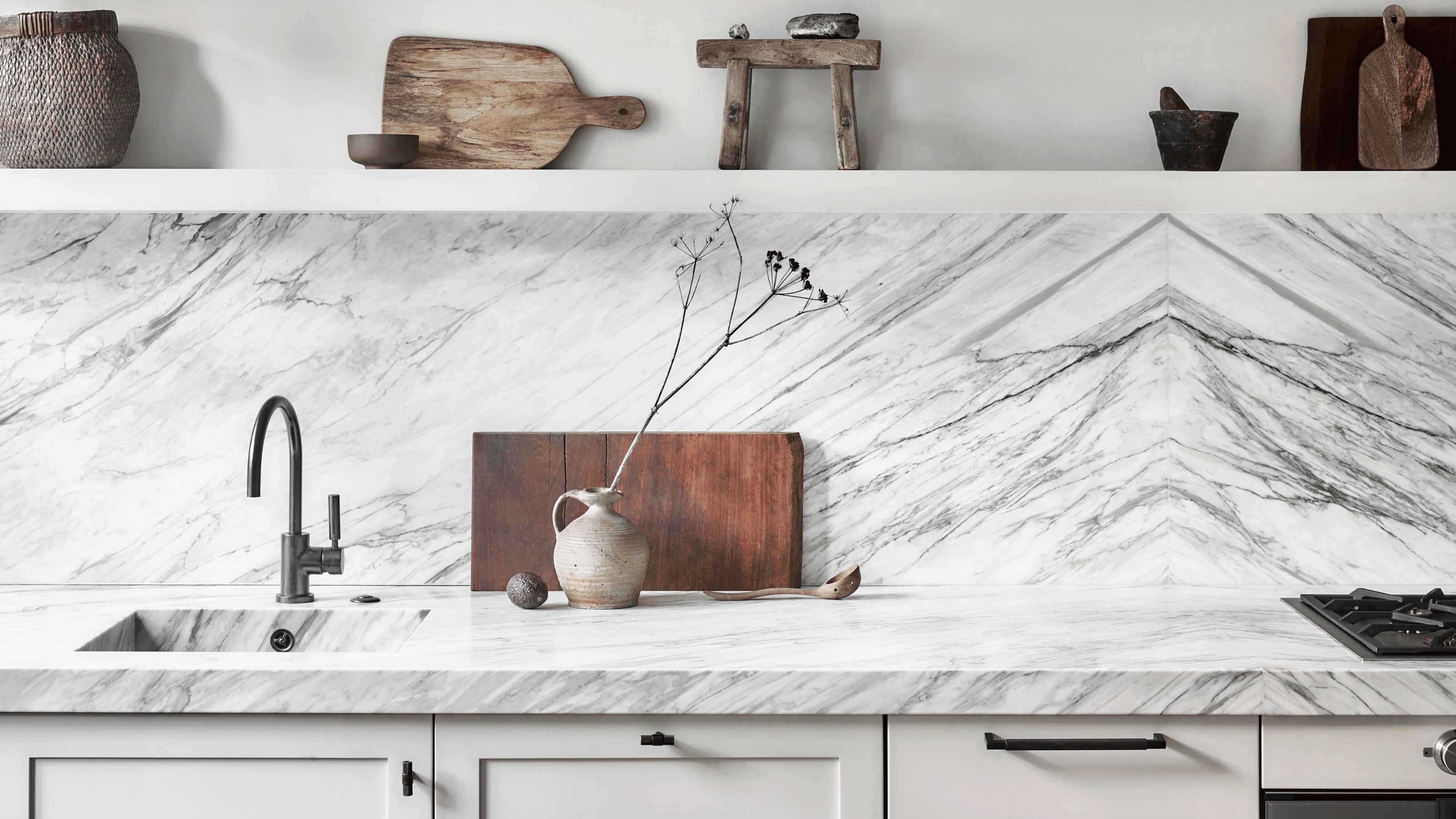 Close up of white marble veining kitchen splashback with shelf and wooden chopping boards