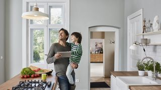 Father and son using a tablet to control a smart light in a kitchen
