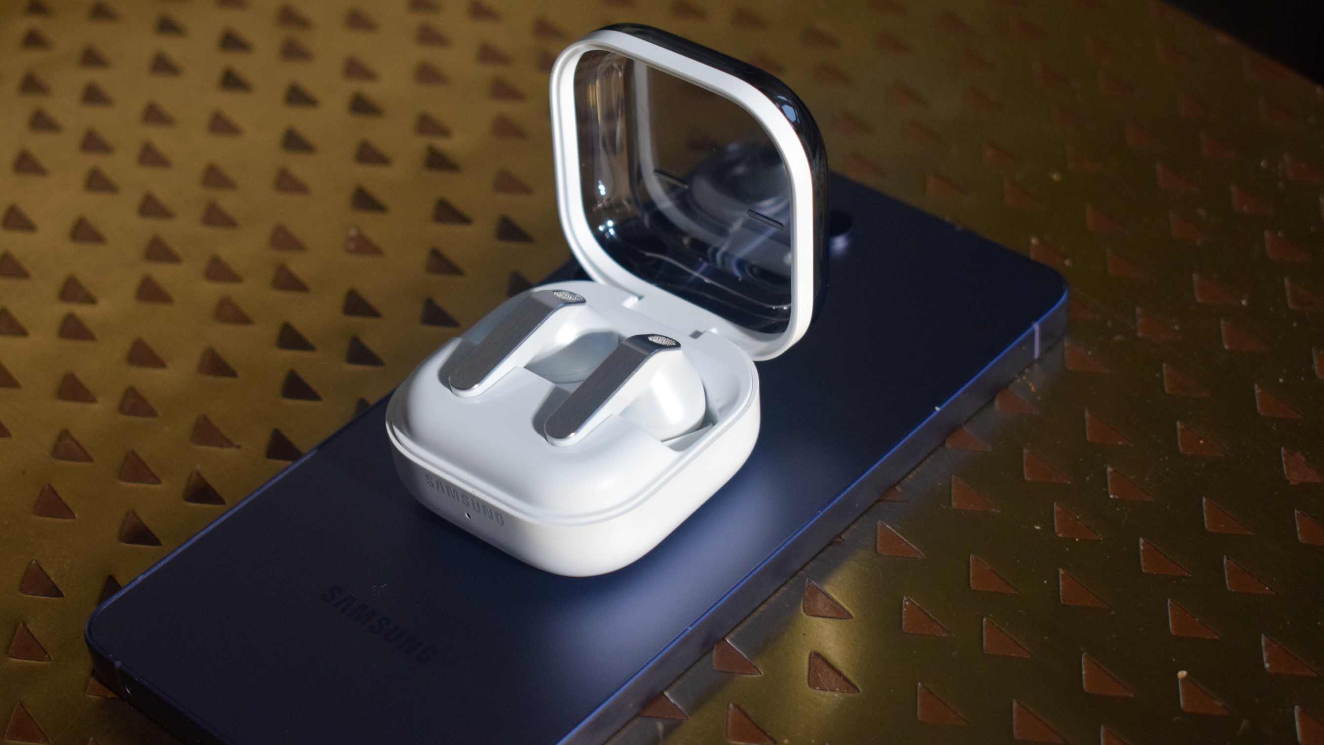 The Samsung Galaxy Buds 4 Pro in their case, atop a Galaxy S26 Ultra.