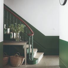 A hallway with two-tone walls in white and green and a staircase