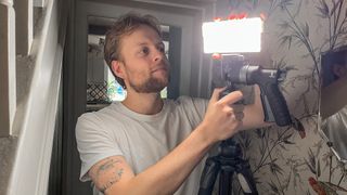 Man turning on LED light panel that's on a tripod