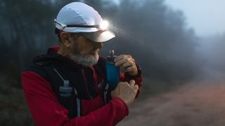 Runner taking soft flask of water out of hydration vest