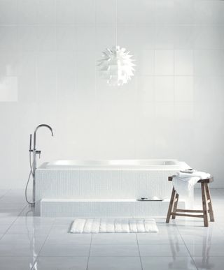white bathroom tile behind contemporary freestanding bath