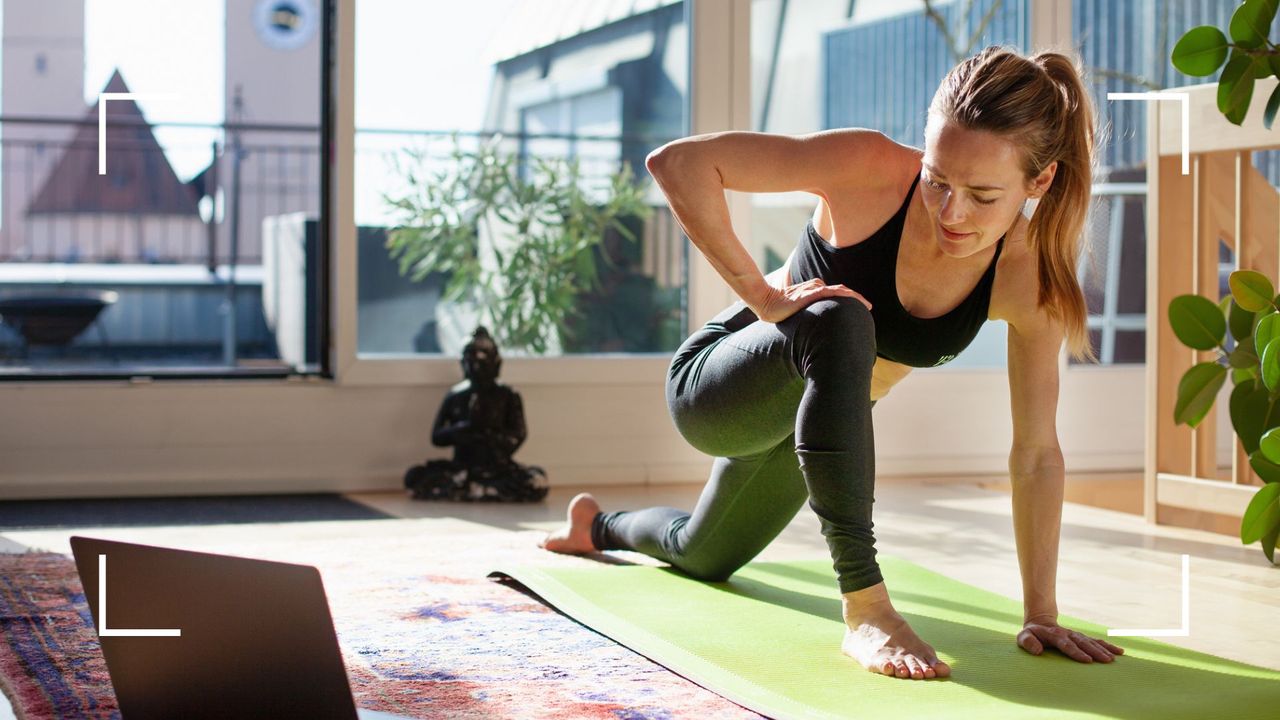 Woman doing yoga over video call in living room surrounded by plants, after learning how to get a flat stomach at any age