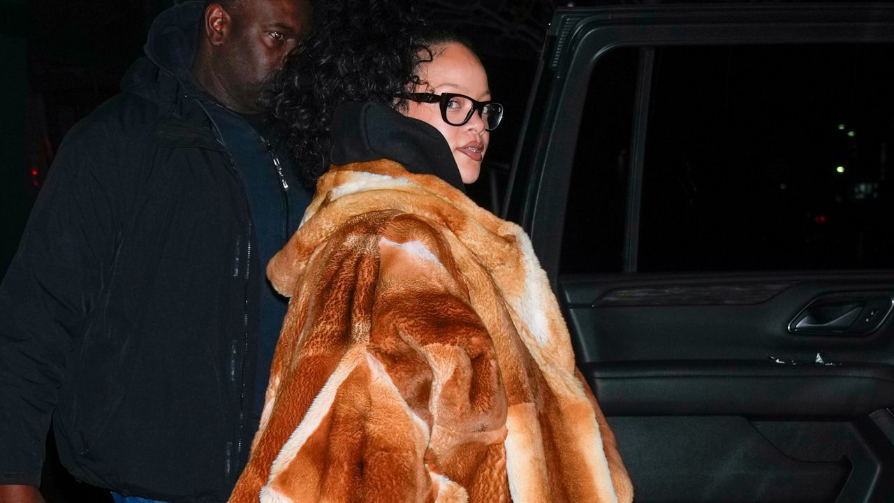 Rihanna gets into a car wearing a fur coat with jeans and clogs