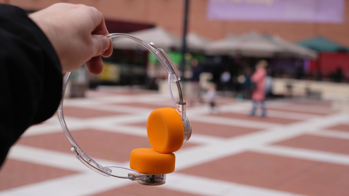 A photograph of the FiiO EH11 on-ear headphones with a transparent frame and orange foam earpads.