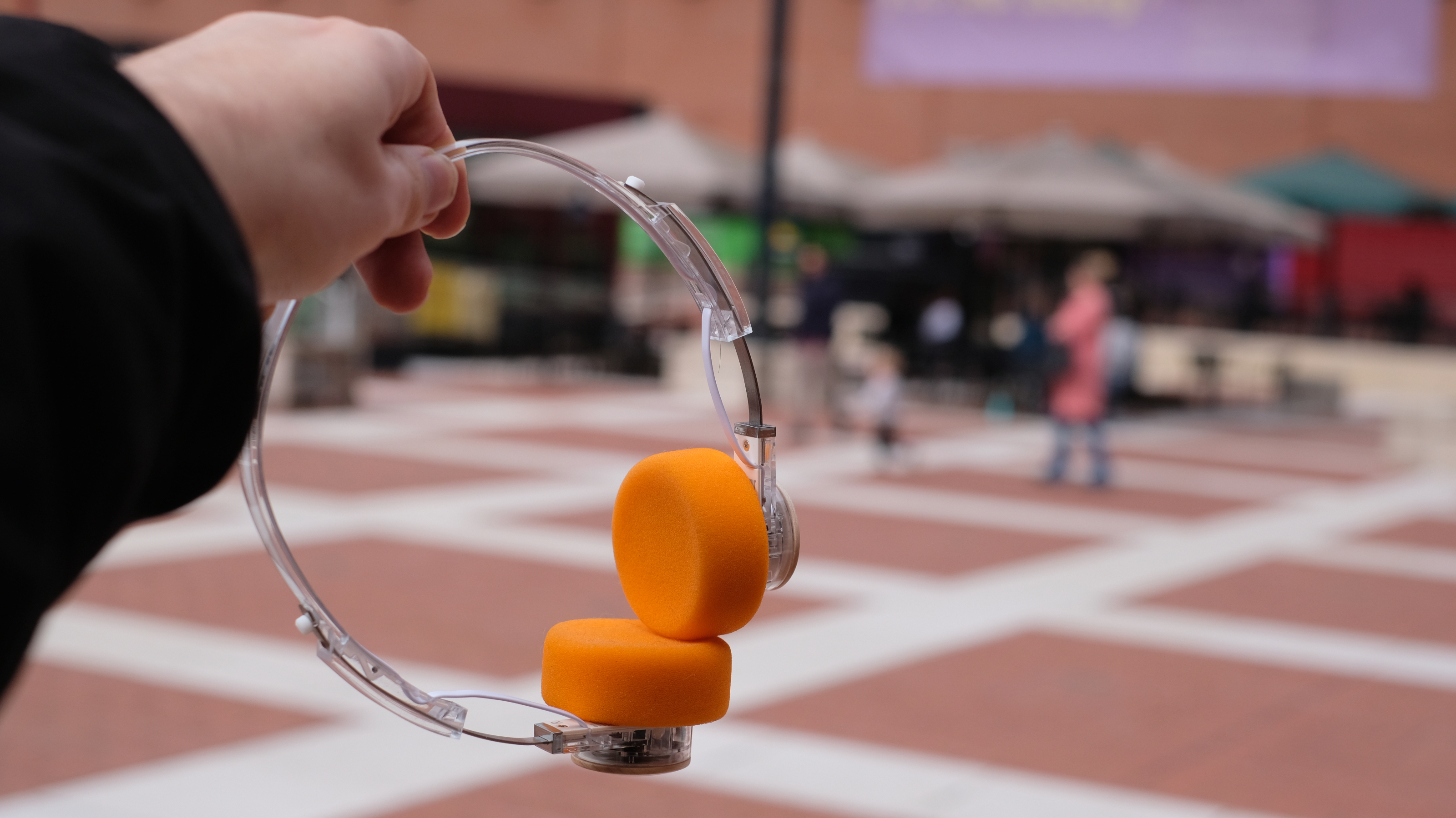 A photograph of the FiiO EH11 over-ear headphones with a transparent frame and orange foam earpads.