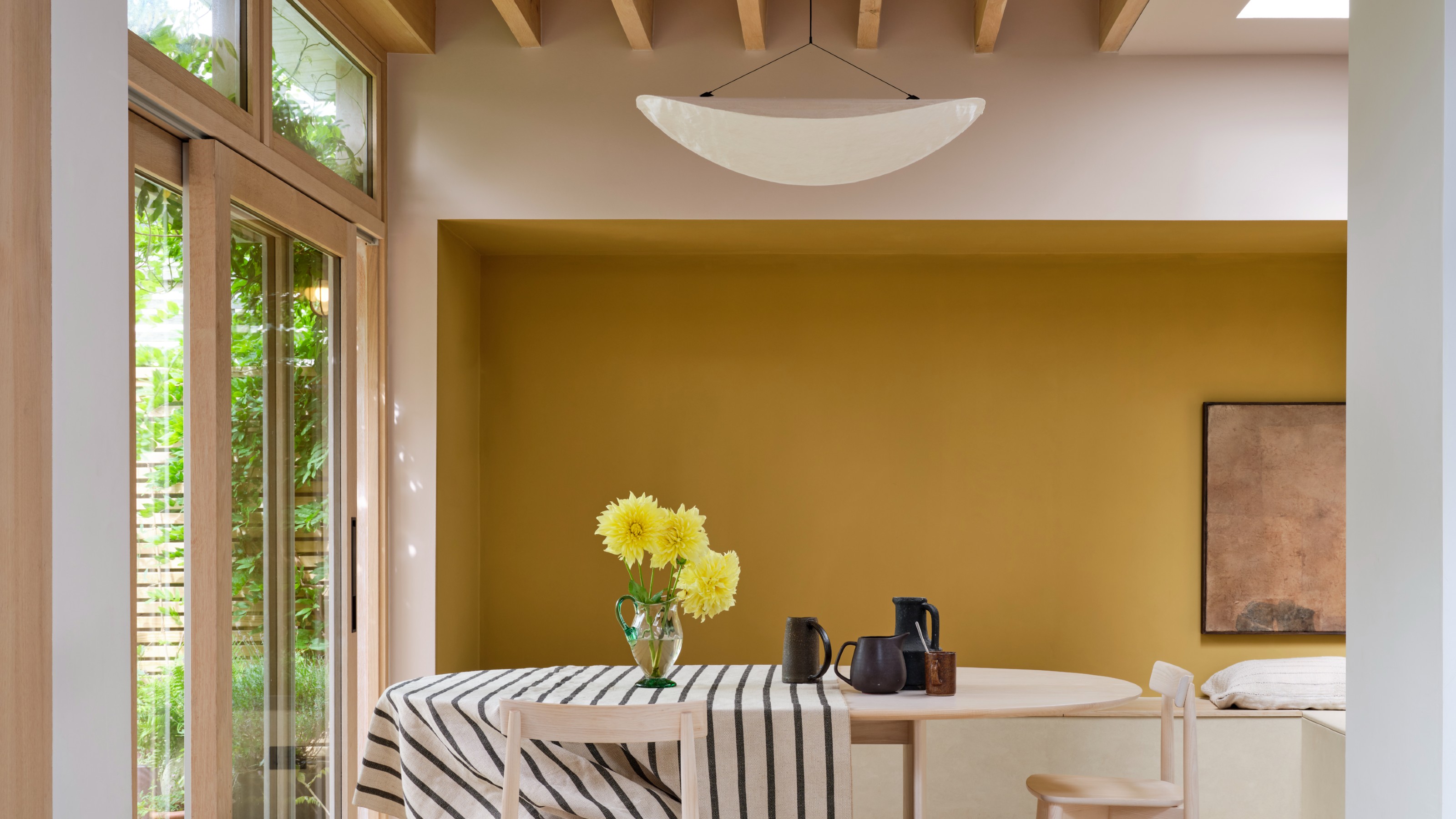 A light and airy dining room with an alcove painted in mustard yellow and the surround in Farrow & Ball Scallop