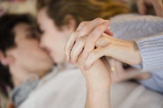 A coouple holding hands while kissing