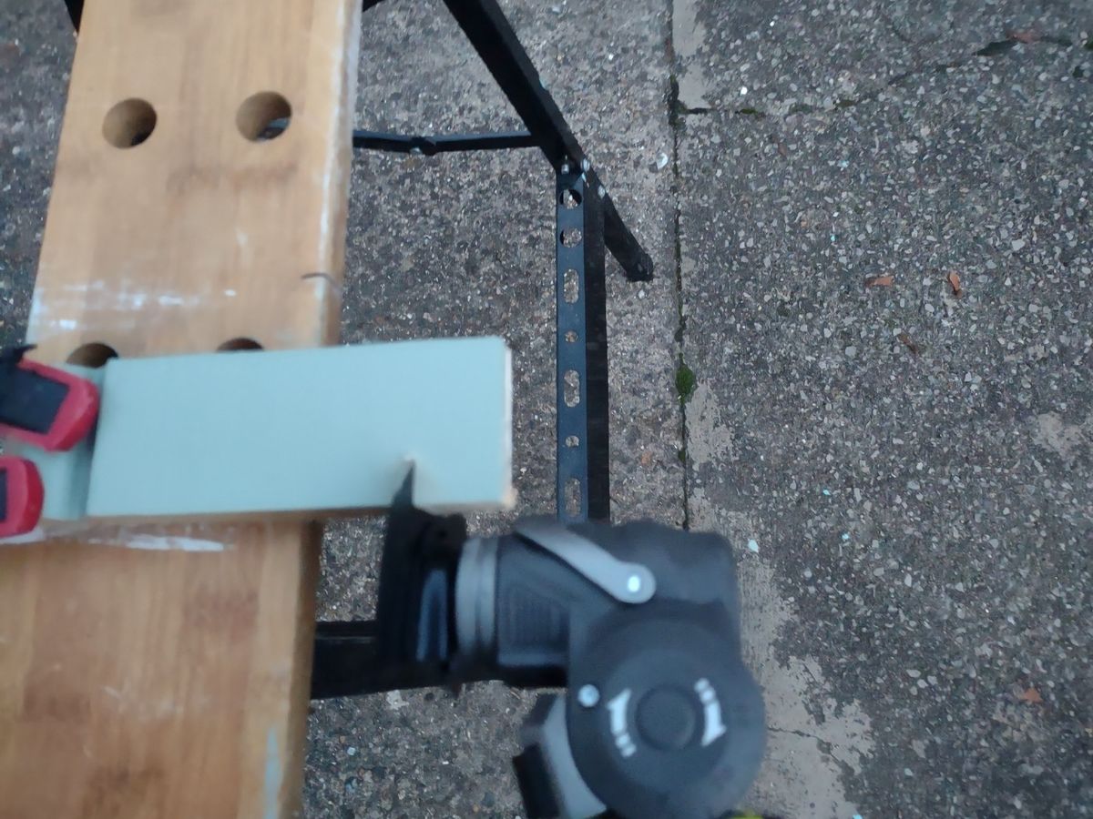 A small piece of wood in a vice being cut with a multitool