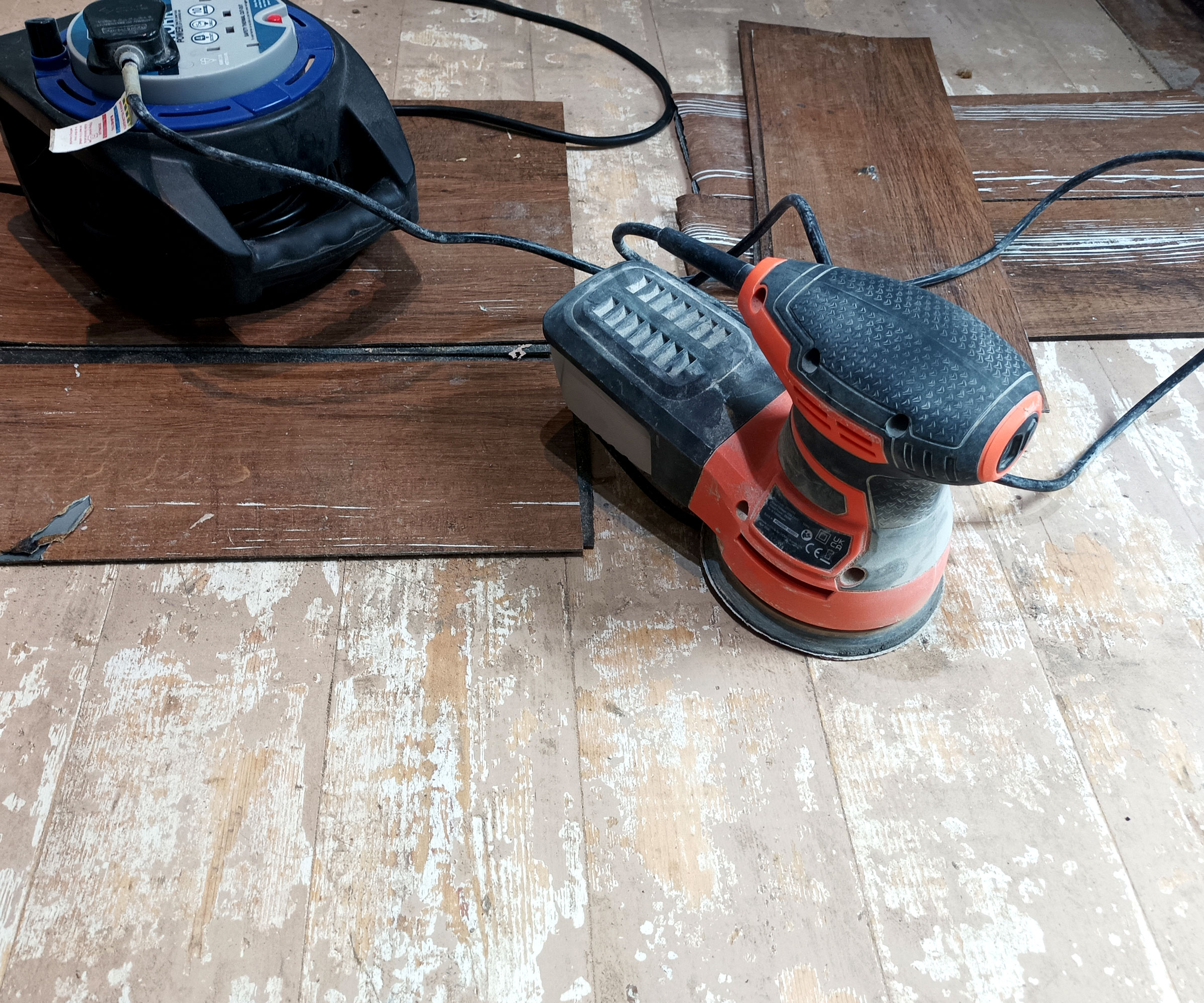 Sander and vinyl planks on a sanded wooden floor