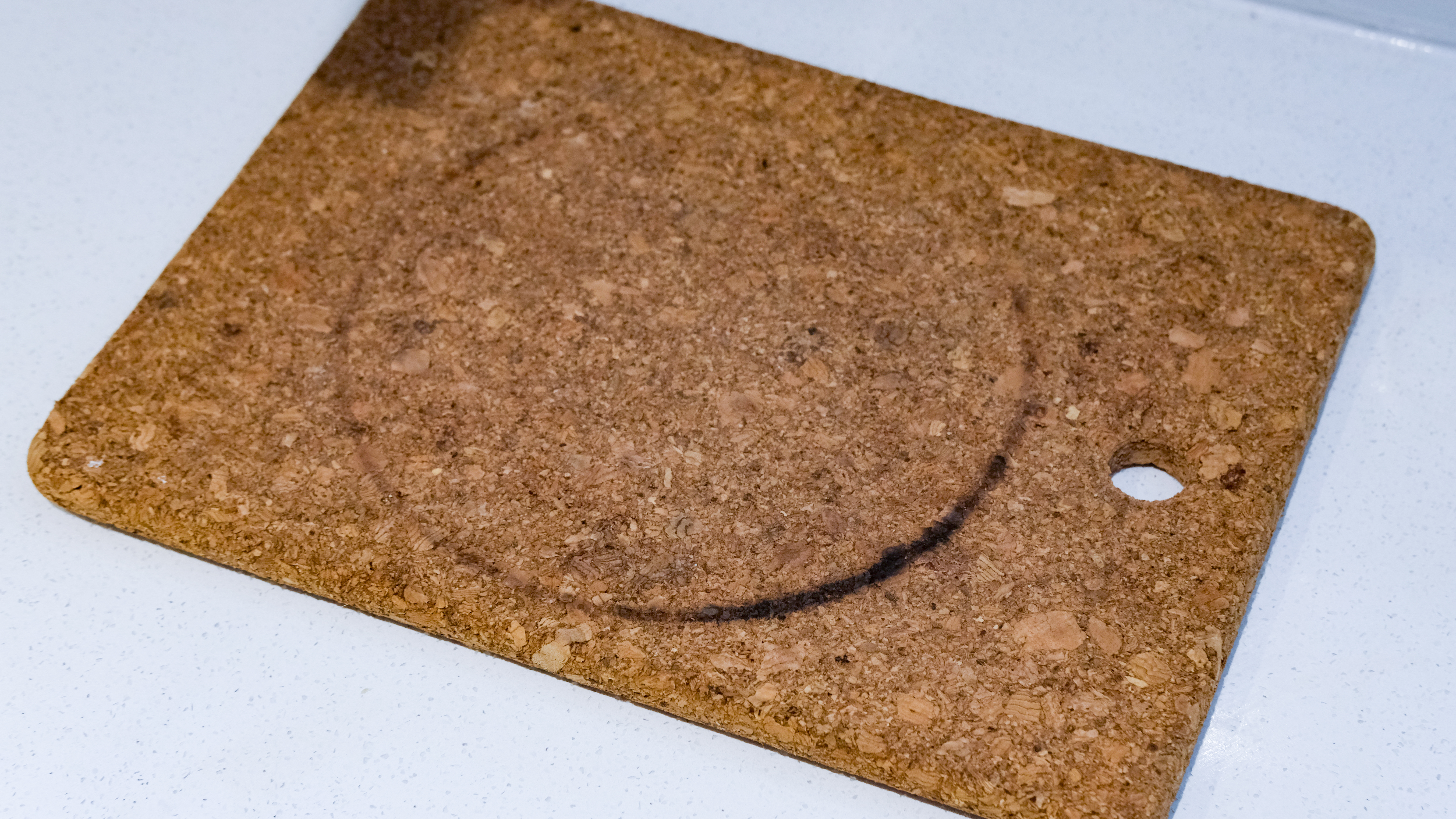 A burned cork heat pad, which has a black ring burned into it by a hot Field Company skillet
