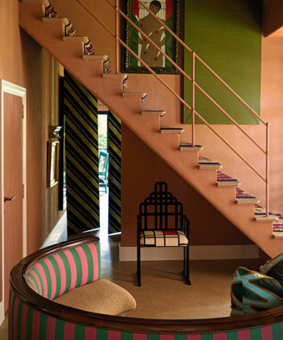 Hallway in peach collour with stairs and curved striped upholstered bench
