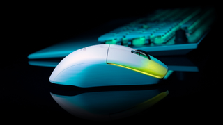 A wireless gaming mouse on a reflective surface next to a keyboard