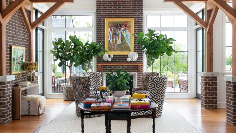 living room with full height ceilings and brickwork with coffee table plants and geometric and floral armchairs