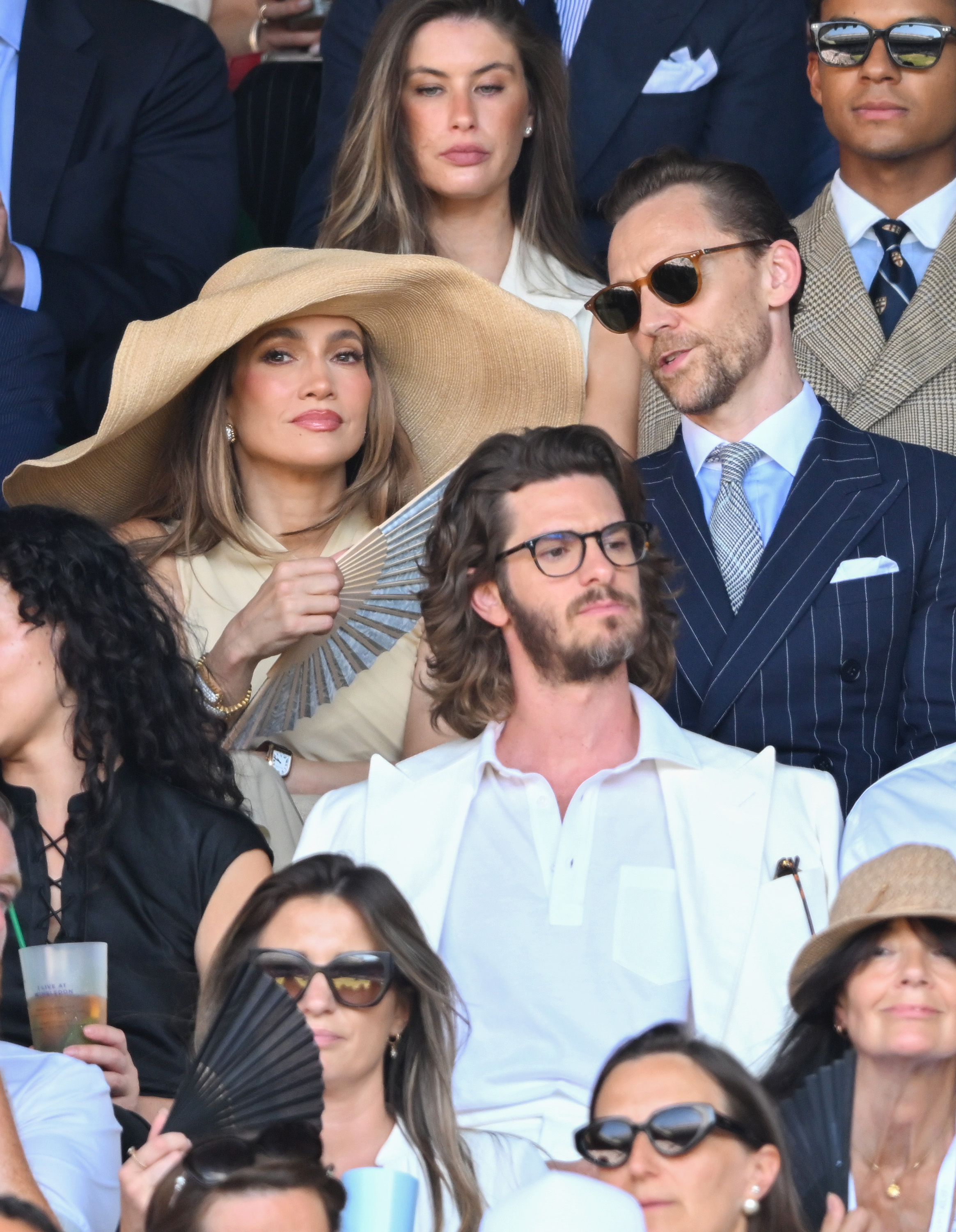 Jennifer Lopez attends Wimbledon on July 12, 2026 wearing a massive raffia hat and a dress from Ralph Lauren, joining Tom Hiddleston who wears a navy pinstripe suit