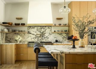 A bright kitchen with wooden cabinetry and marble counter tops