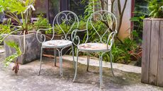 two rusty metal garden chairs on a patio