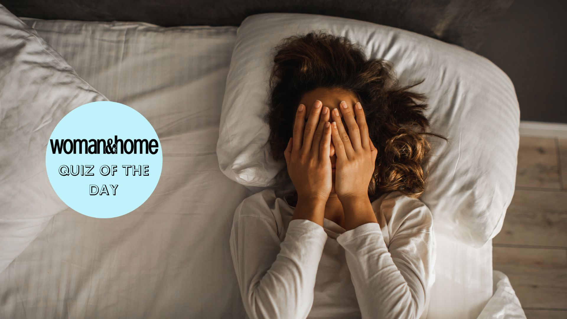 A woman in bed with her hands to her face