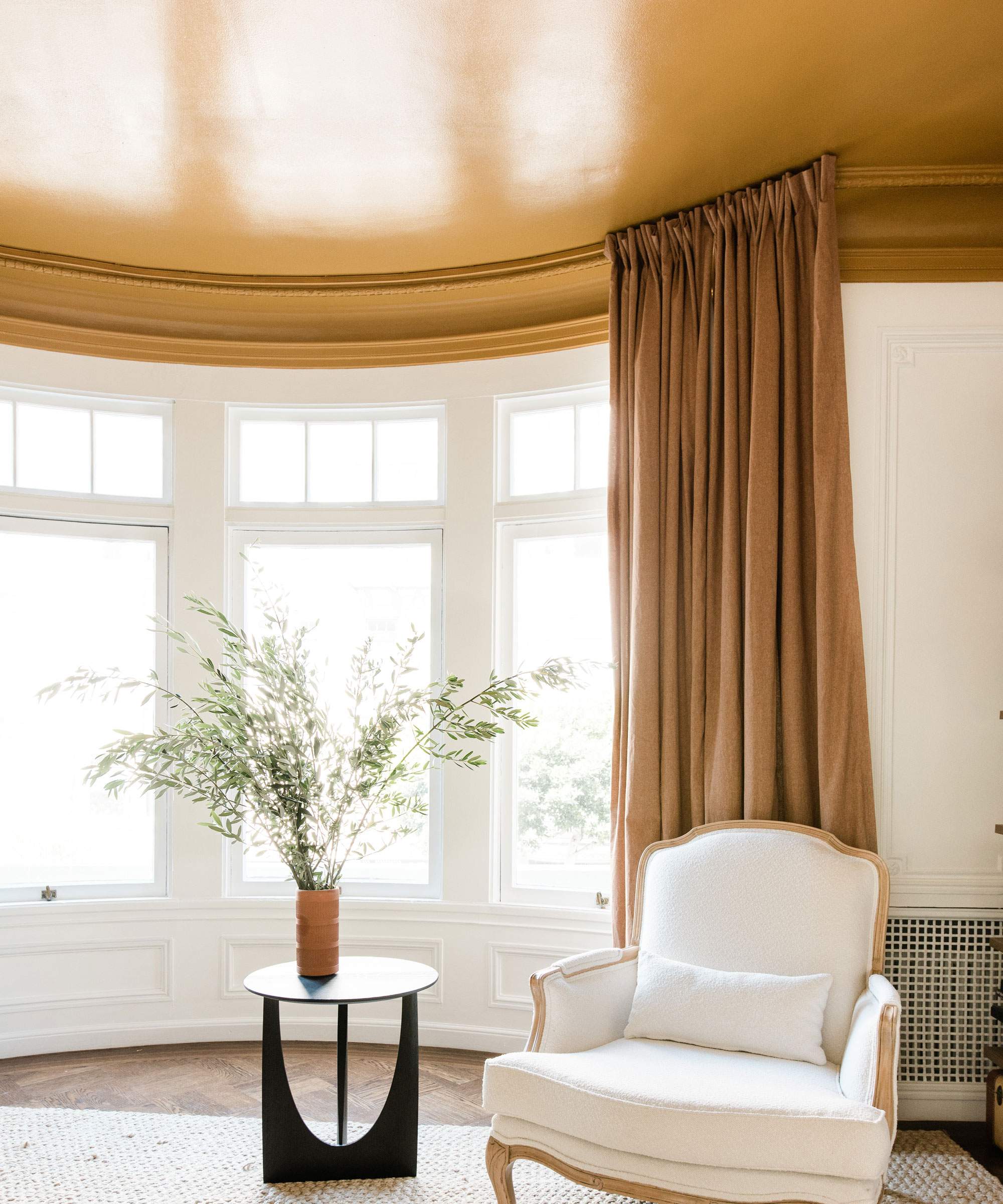 White walls and yellow contrast ceiling in bedroom with yellow drapes framing bay windows