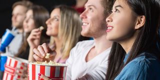 Movie theatergoers eating popcorn in MAD_Production/Shutterstock photo
