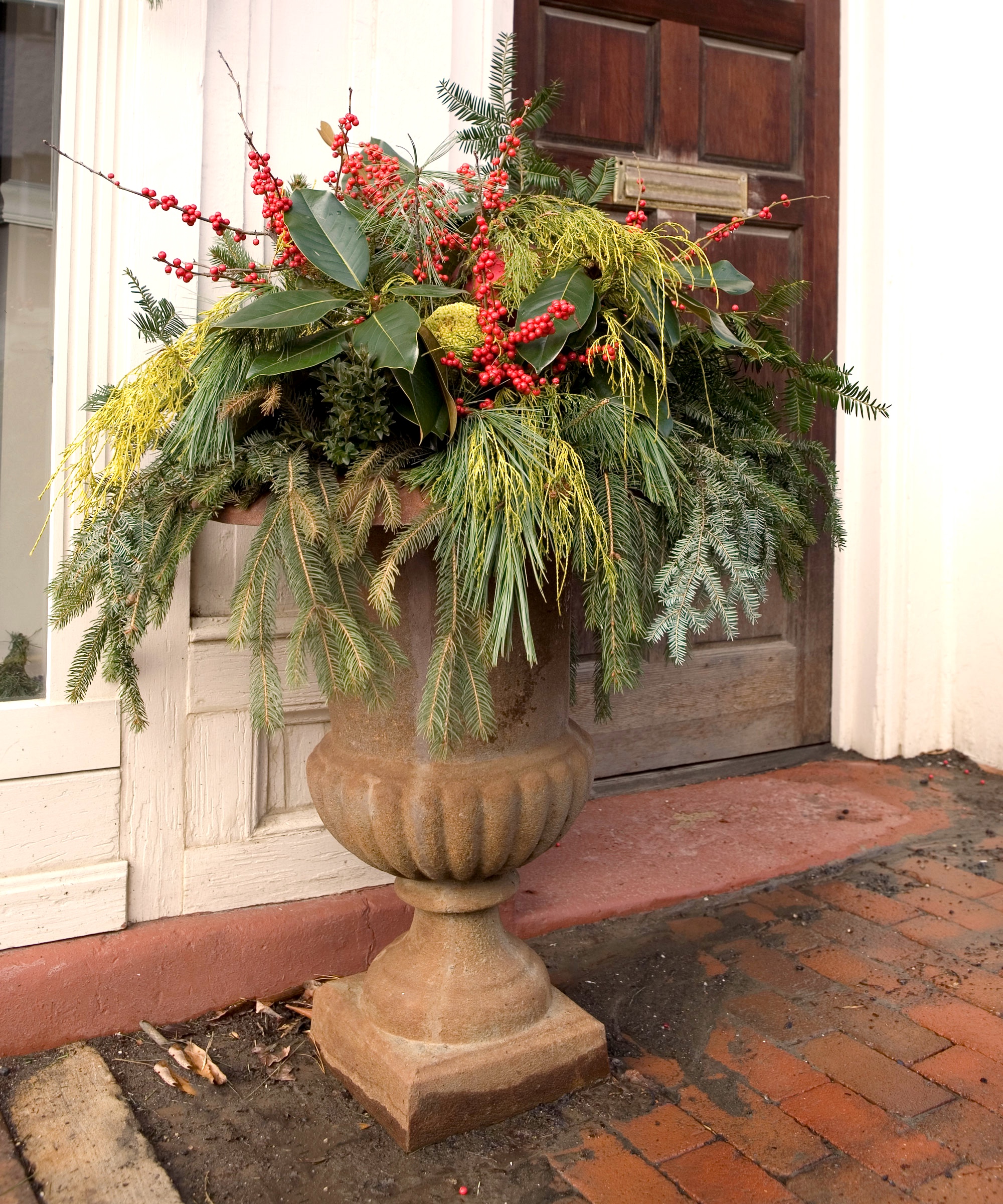 festive container with broom, evergreens and berries