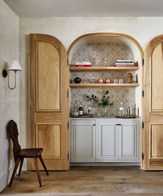 An arched home bar with open wooden doors