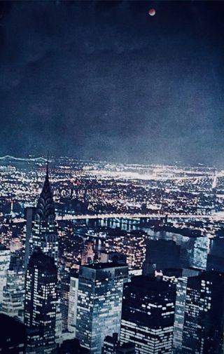 A dramatic view of a totally eclipsed full moon shining above the skyscrapers of Manhattan as seen from the 86th floor Observation Deck of the Empire State Building on the evening of Nov. 18, 1975. This was a 6-second exposure taken using a Nikormatte camera body, with Kodachrome-64 film.