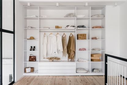 An open closet with white shelves and organized clothes 