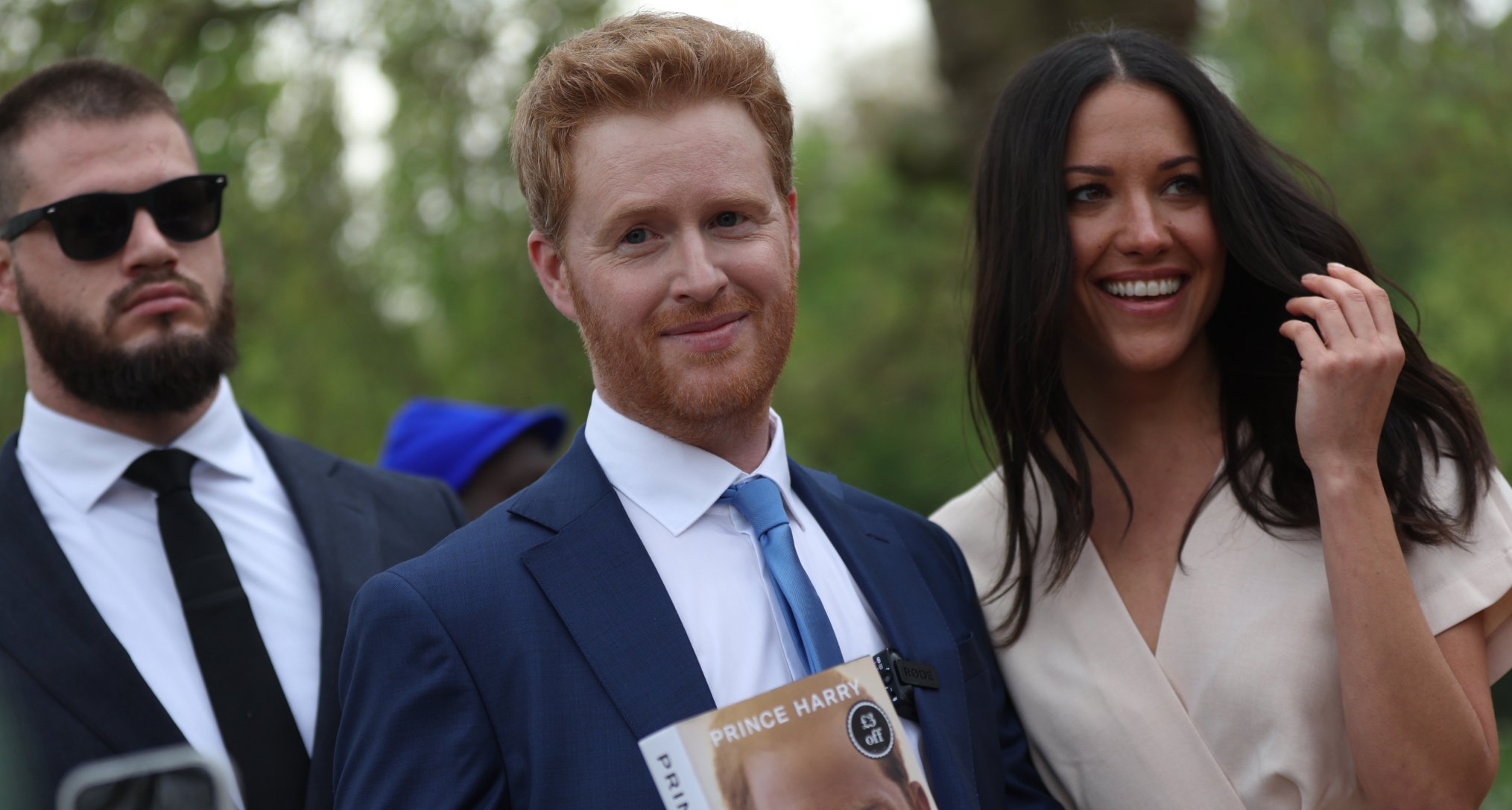 Prince Harry and Meghan Markle impersonators Rhys Whittock and Sarah Mhlanga posing with a copy of Spare
