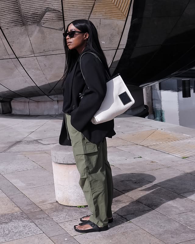 @_loissterling wears a pair of khaki cargo trousers with flip flops and a black jumper