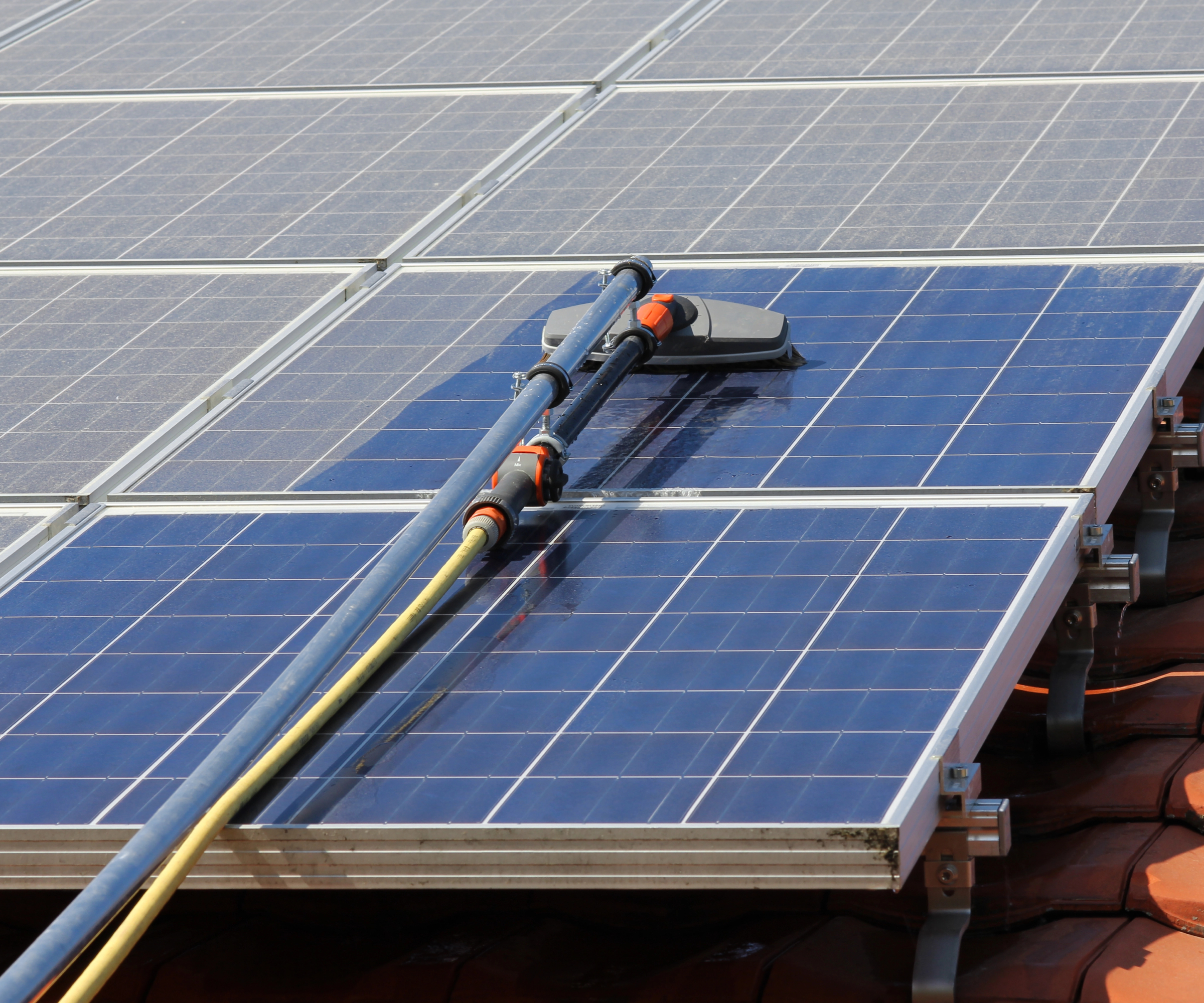 solar panels on roof being cleaned with professional hose and brush