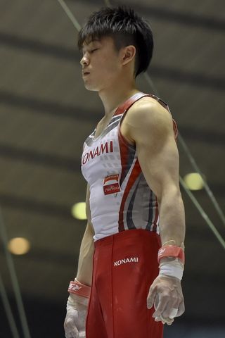 A gymnast closes his eyes to focus before a competition