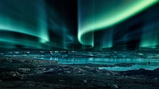 swirls of northern lights above lake in Greenland