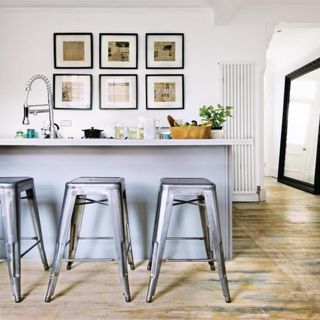 kitchen with white wall frames on wall bar stools and wooden flooring