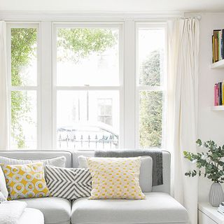White living room with large windows, grey sofa and scatter cushions