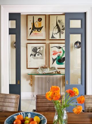 Hallway painted in beige with blue door and framed art work on walls