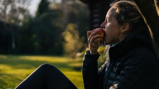 Woman sitting outside eating an apple