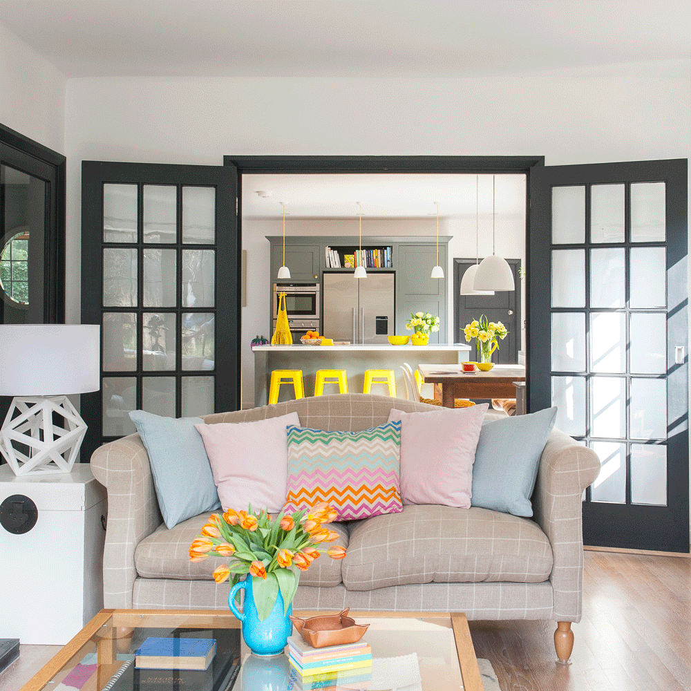 living area and kitchen with wooden floor and sofa with cushions and yellow stools