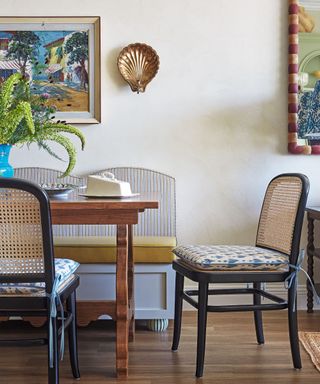 dining table with patterned cushions and bench and artwork behind