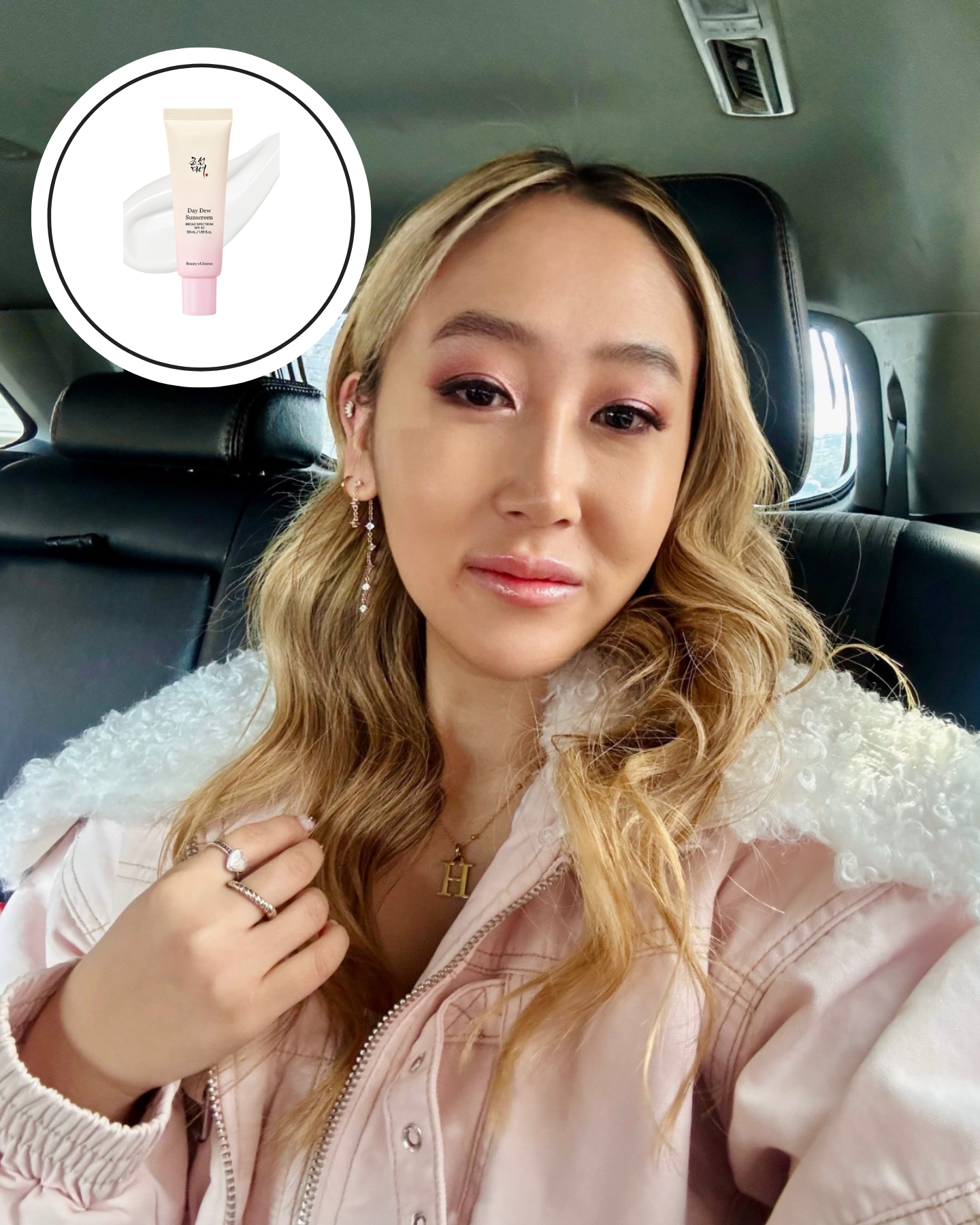 a woman in a pink shirt with blonde curly hair looking at the camera in a car