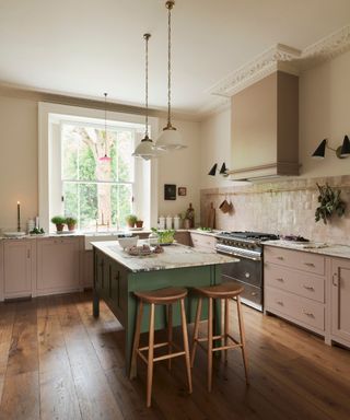 A pink kitchen with a green kitchen island