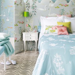 Grey patterned carpet with blue patterned bed, blue patterned wallpaper and white bedside table