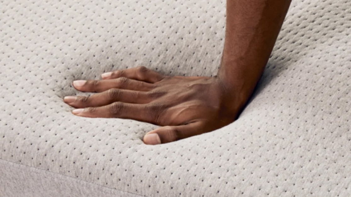A close up of a hand pressing into the surface of the Casper Cloud One mattress, feeling the plush foams beneath