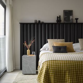 monochrome bedroom with ochre blanket, and oversized headboard