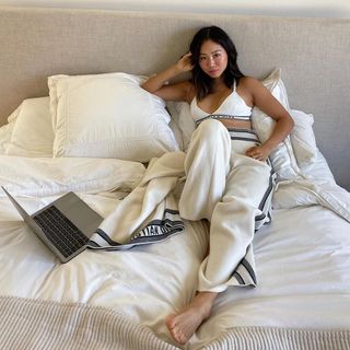 Content creator Aimee Song lies in bed with her laptop