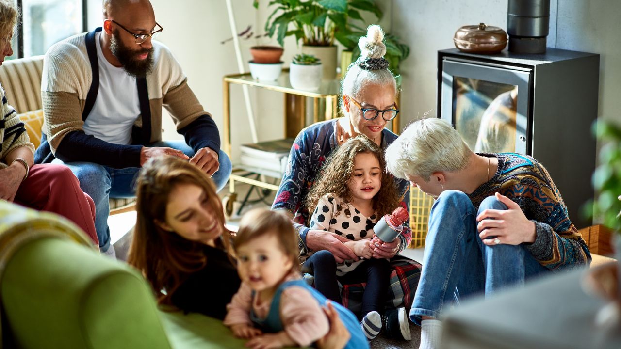 Multiple generations of a family are gathered in a living room.