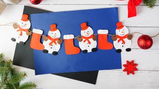 paper gardland of red stocking and snowmen against a blue envelope