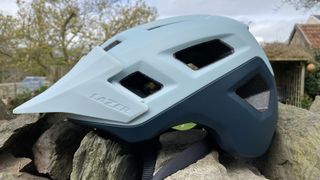 Side view of Lazer Coyote KinetiCore mountain bike helmet on a stone wall